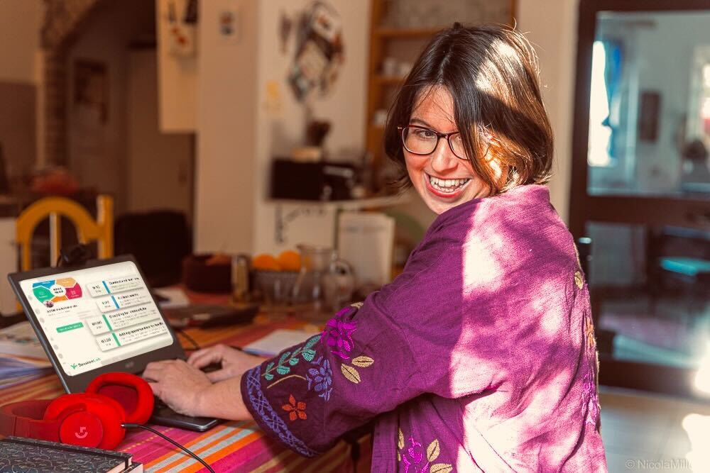 A woman working at her desk with the SessionLab planner on her computer screen