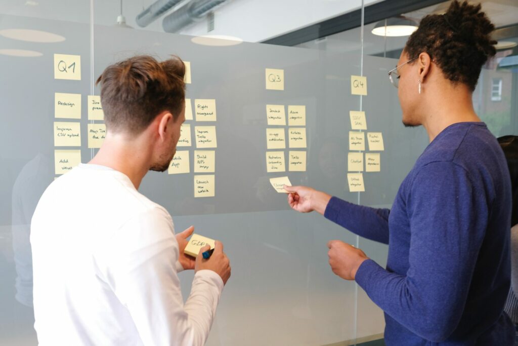 Two people working with sticky notes on a board