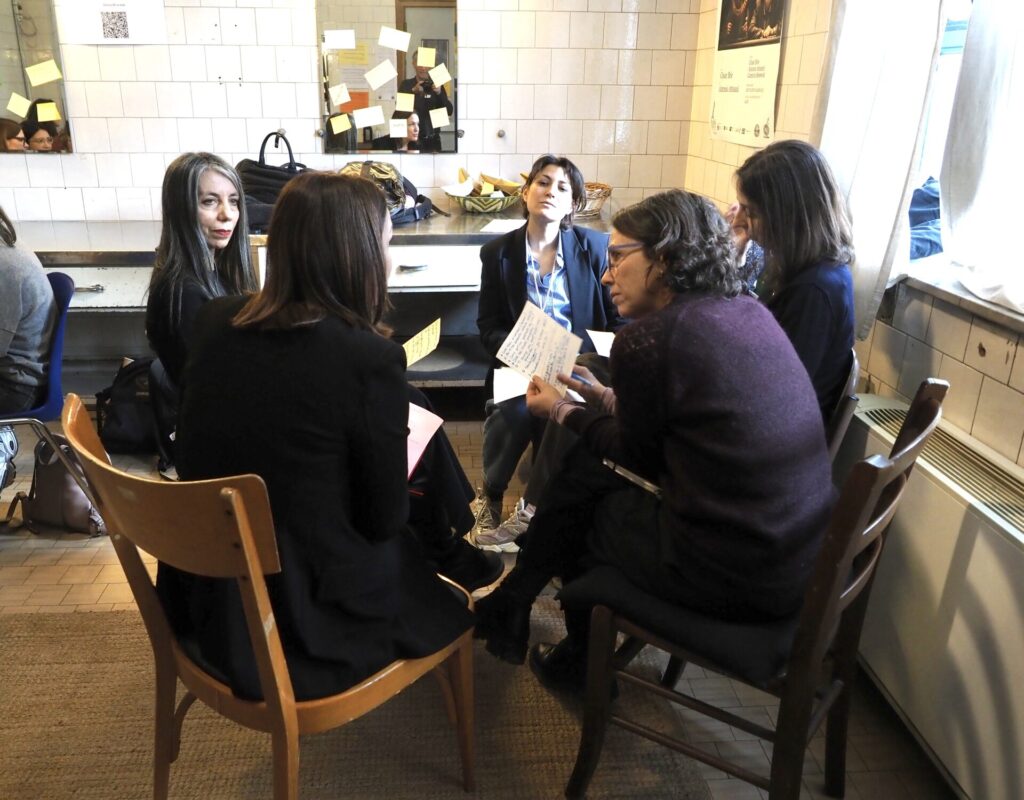a group of 5 professional women sitting in a circle talking