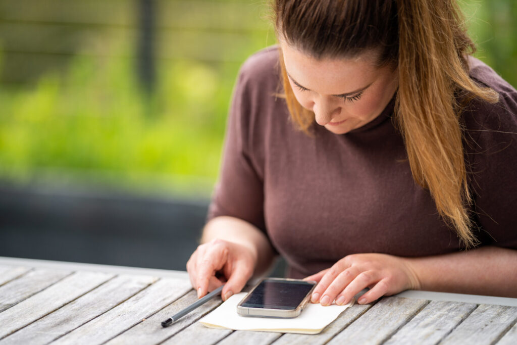 A woman seated outdoors working on her phone