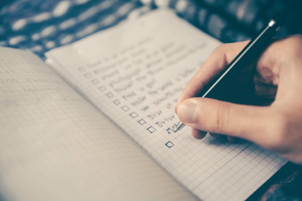 Close up of a hand holding a pen and writing in a checklist